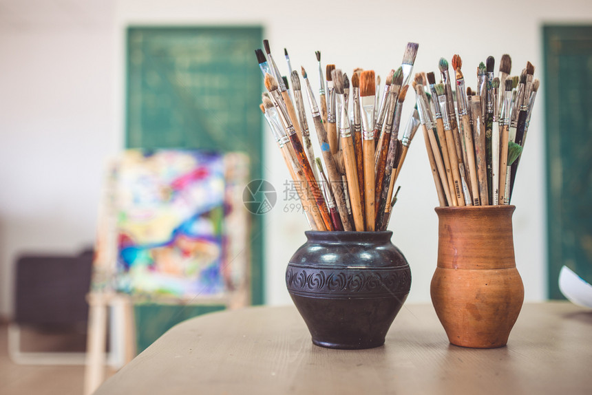 一堆艺术刷子站在陶瓷花瓶的桌上在艺术工作室的桌子上一堆艺术刷子站在陶瓷花瓶的桌子上在艺术工作室的桌子上图片