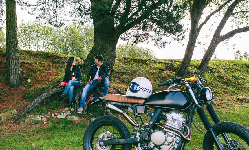 有选择地关注背景中的夫妻妇在摩托车旅行中休息图片