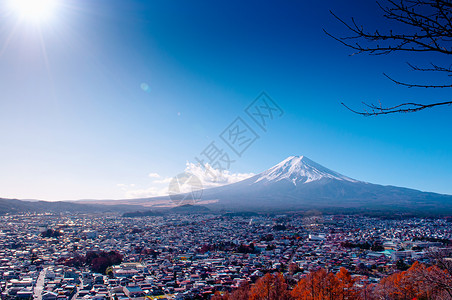 在河口谷附近的fujiyoshda公园中看到有雪和蓝天太阳耀斑的fuji山有彩色秋树和香木的Shimoysda城市在川口果附近的背景图片