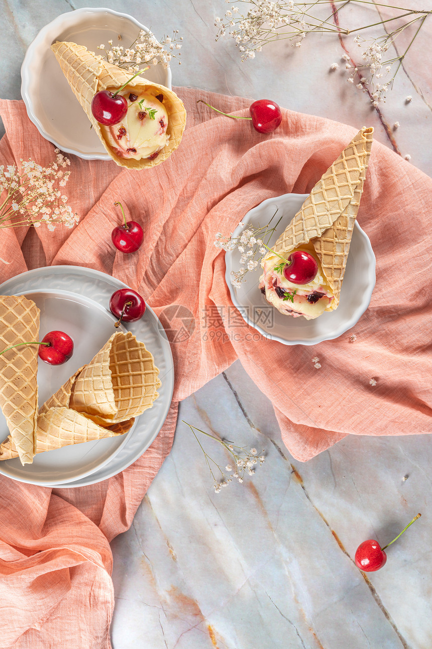 大理石表面有冰淇淋和樱桃水果的传统华夫饼锥图片