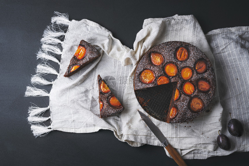 美味的梅子加巧克力和两片白厨房毛巾黑桌子上面是秋天甜食平整的秋天甜点图片