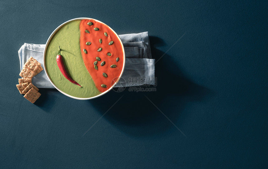 汤碗番茄和菠菜放在蓝桌顶上碗里红色和绿奶油汤的上面健康食物放在阳光下图片