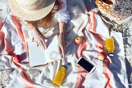 以面包苹果和汁为野餐篮子女孩在野餐谎言上读书图片