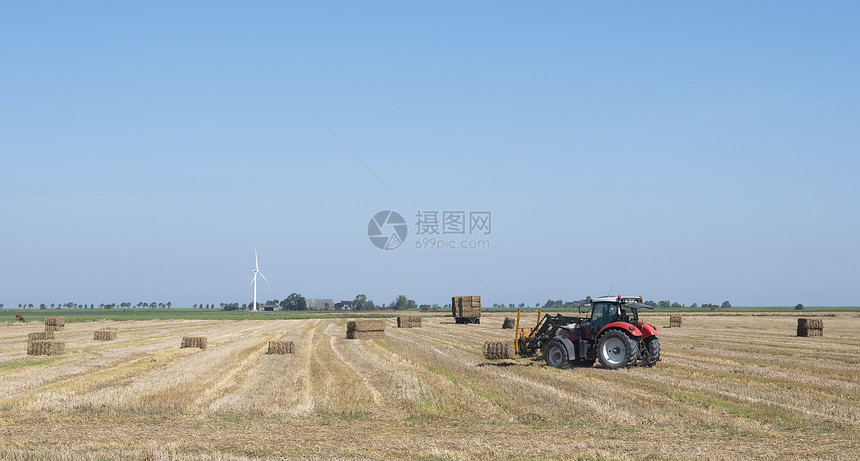 阳光明媚的夏日在甘蓝天之下在杜楚省农用拖拉机和一起收集草篮图片