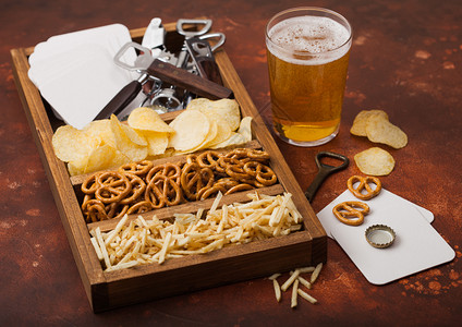 棕色厨房餐桌背景上装着一盒零食的杯式啤酒和开瓶器高清图片