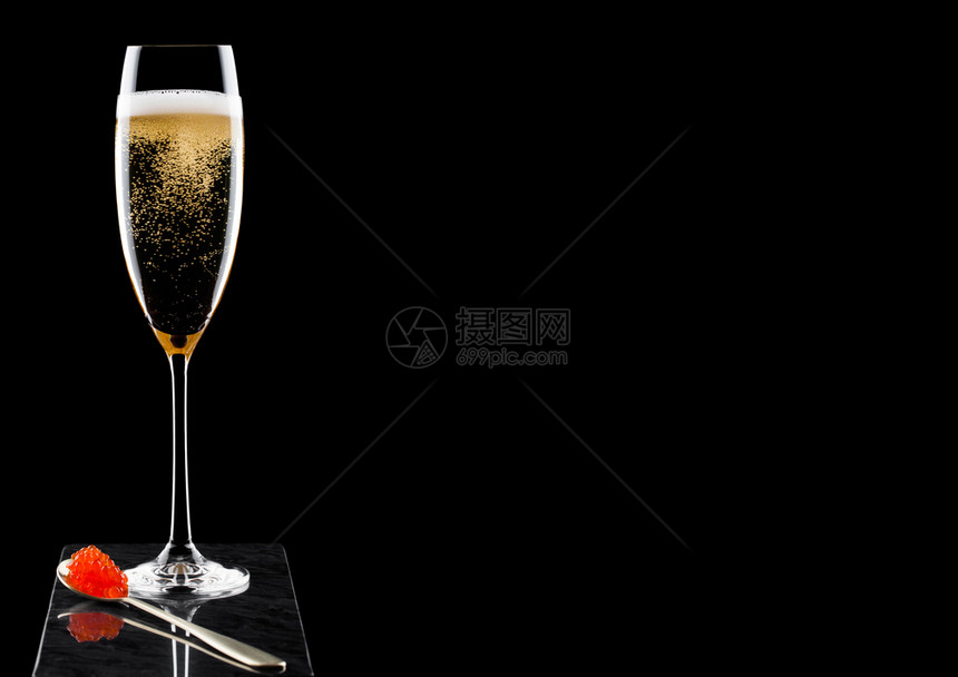 优雅的黄色香槟杯子黑大理石板上的金子勺配红色的鱼酱图片