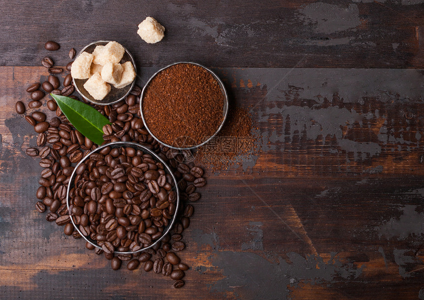 含有地面粉末和甘蔗糖立方块的原有机新鲜咖啡豆木材上图片