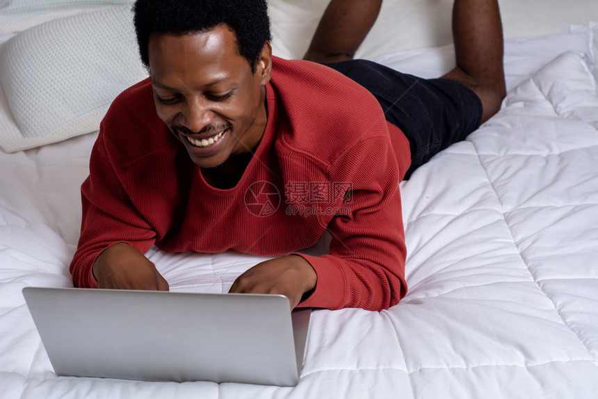 美国年轻人在床上用笔记本电脑图片