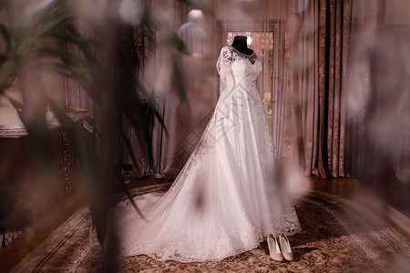 时髦的丝绸婚纱挂在酒店木房的衣架上早准备婚礼概念旧纱时尚和美丽的婚纱经典丝绸挂在酒店木房的衣架上背景图片