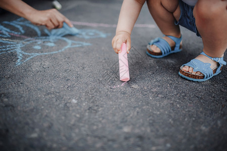 女孩在人行道上画着粉笔小孩在人行道上画着粉笔小女孩在人行道上画着粉笔图片