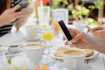 在咖啡店使用智能手机的朋友团体交流概念图片