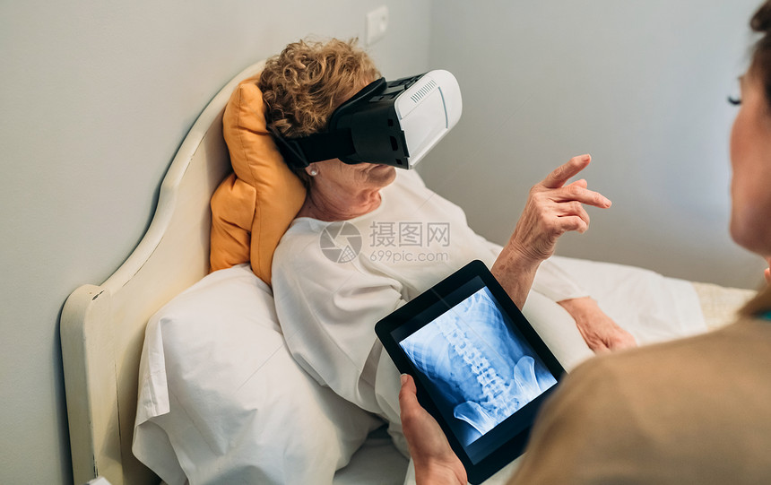 更年长的病人使用虚拟现实眼镜去看脊椎而女医生解释图片