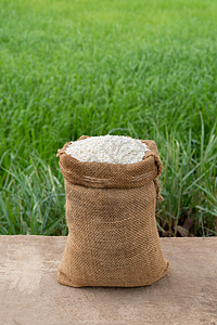 以稻田背景为的木桌布袋中的茉花大米图片