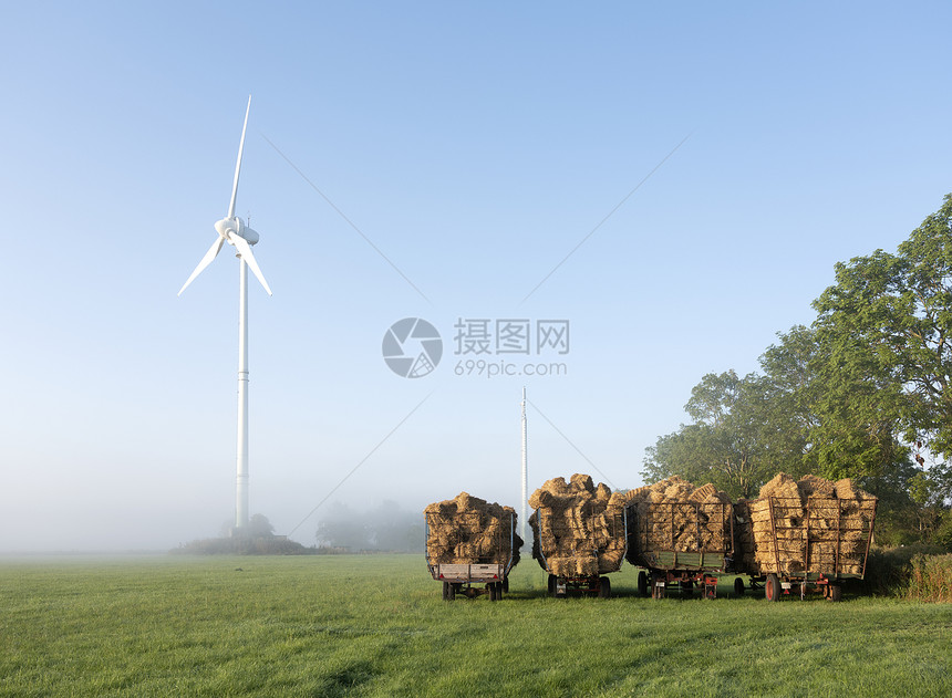 在薄雾清晨草地上的风力发电车图片
