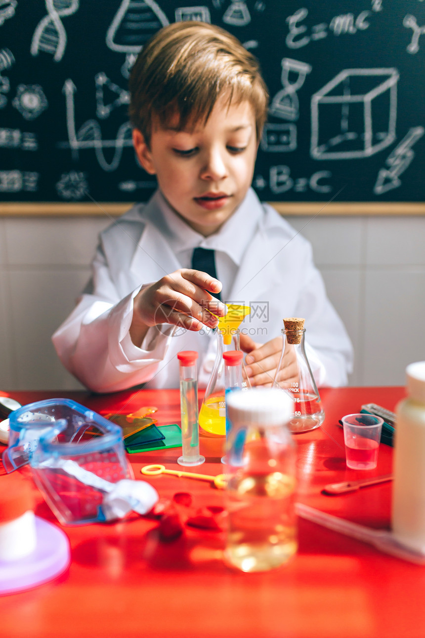 男孩打扮成化学家在黑板前玩化学游戏图片
