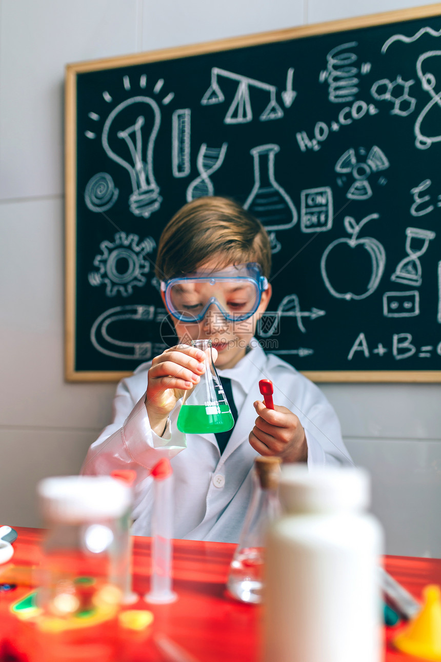 男孩打扮成化学家在黑板前玩化学游戏图片