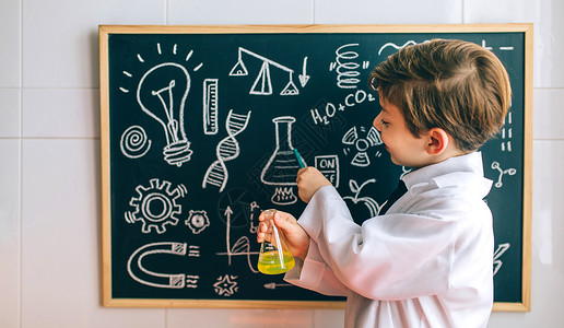 男孩打扮成化学家拿着瓶子指黑板图片