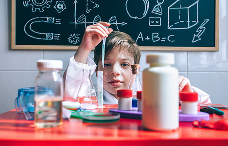 小男孩科学家肖像他们用化学玩具从桌子后面的试验管提取液体图片