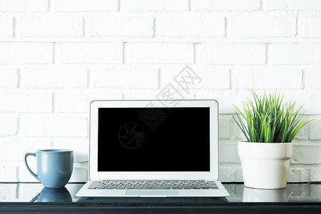 书桌桌面白色在屏幕上空着笔记本电脑咖啡杯和绿色植物锅放在桌上商业和技术工作空间概念背景