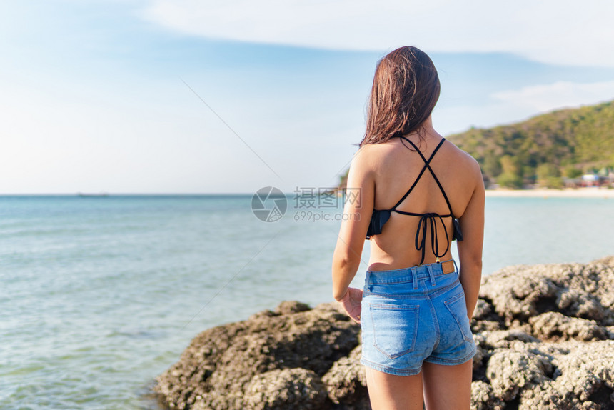 身穿比基尼的年轻女站在海面对图片