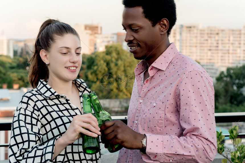一群年轻的多民族朋友在户外屋顶庆祝喝瓶酒玩得开心图片