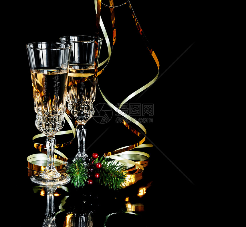 两杯香槟晶和两金色蛇纹在黑背景上隔离有文字空间图片