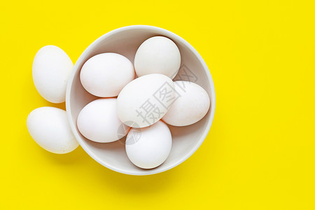 顶视图黄色背景碗里的白鸡蛋背景图片