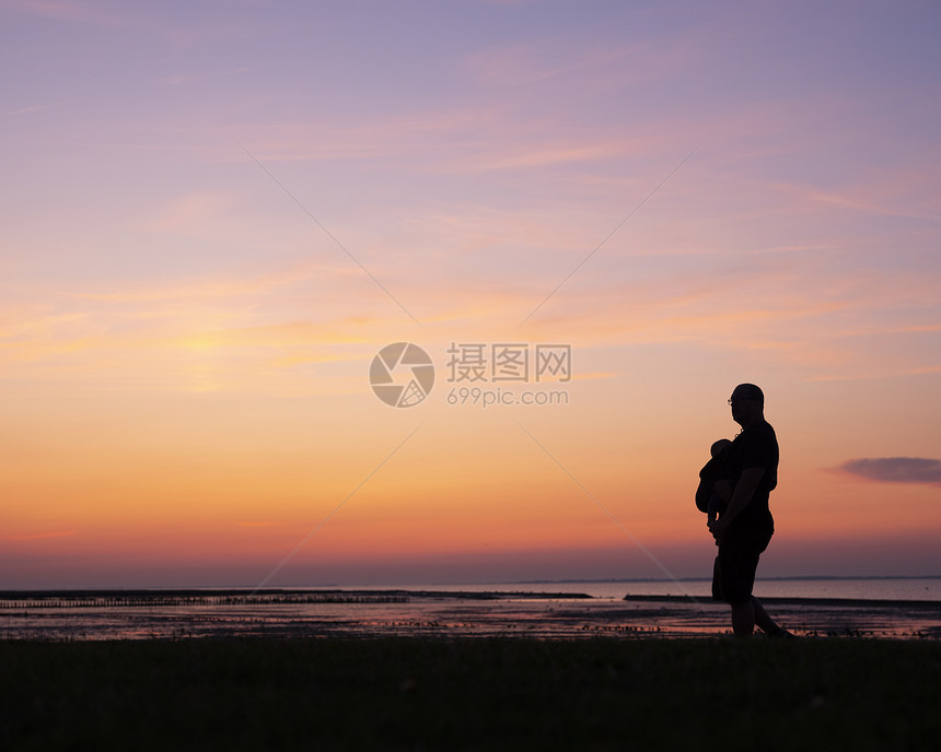 带着孩子在肚中行走的父亲背影面对多彩的日落图片