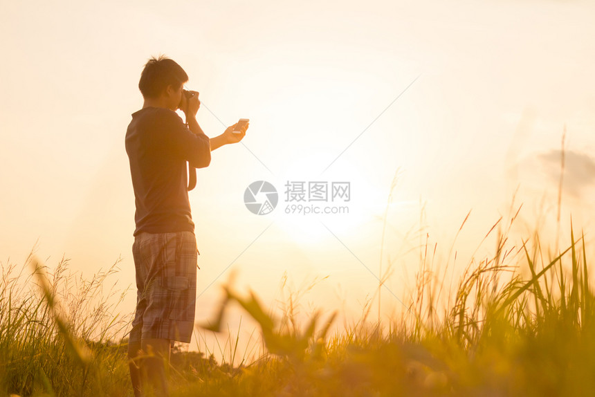 年轻人正在看日落带着相机旅行图片