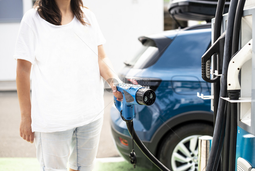 妇女收费电动汽车电源插座绿色生态概念图片