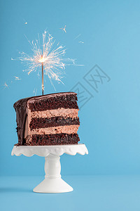 生日概念巧克力层蛋糕上面有火花蓝色的桌子新年框架蛋糕和烟花背景图片
