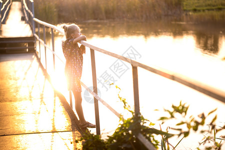 小女孩站在桥上看着日落图片