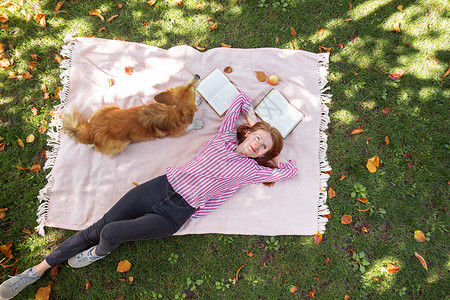 女孩和狗合唱团躺在草坪上看书图片