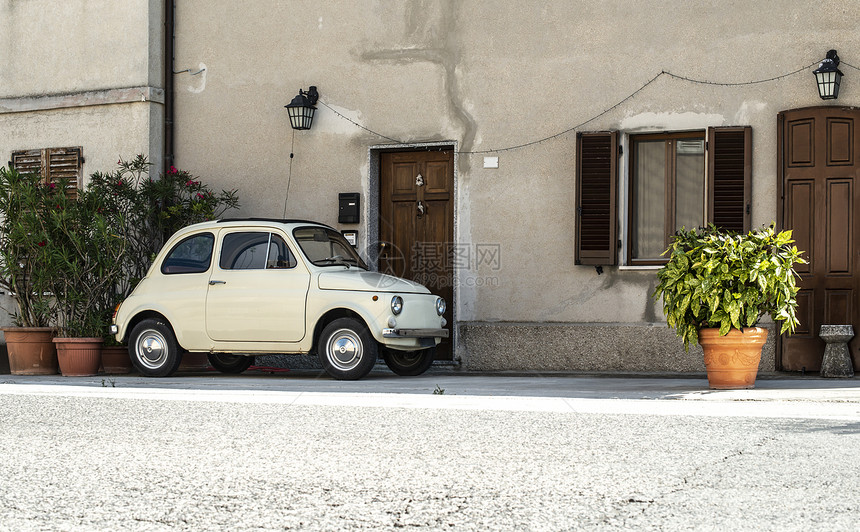 旧型意大利车色的在房子外墙和鲜花前图片