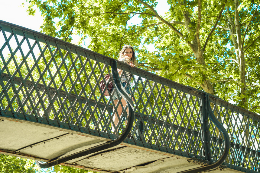 在公园里桥上年轻女游客图片