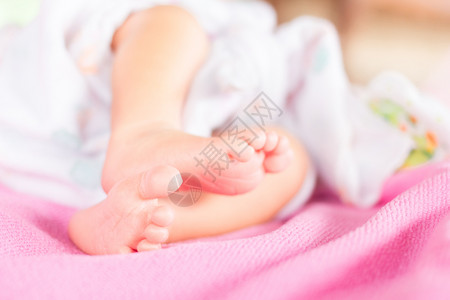轻柔的新生婴儿脚对着粉红色的毯子背景图片
