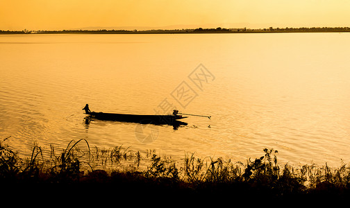 一只独自的渔民在小船上湖走出去太阳破晓夜晚背景图片