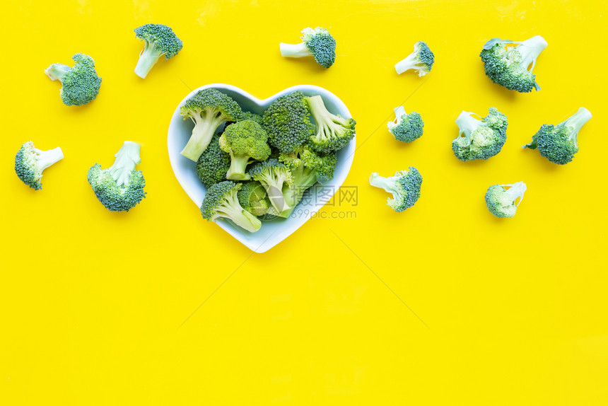 黄色背景上有心形碗的新鲜花椰菜复制空格图片