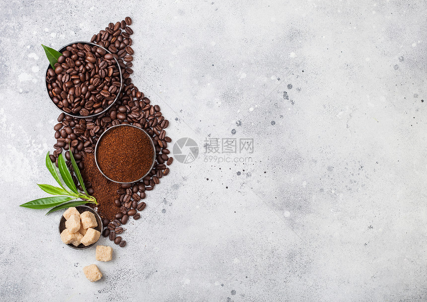 含有地面粉末和甘蔗糖立方体的新鲜有机咖啡豆轻厨房桌上有咖啡树叶图片