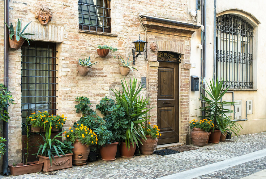 在意大利小街上的旧建筑在意大利小街的狭窄道上在古老房屋前的鲜花图片