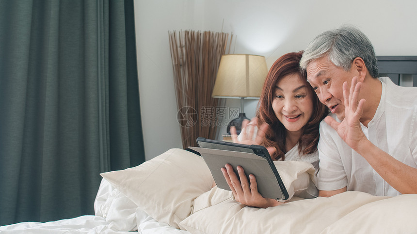 老年夫妇在床上用平板电脑和孙女打视频电话图片