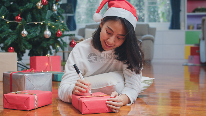 女青少年穿着毛衣和圣塔帽子放松快乐在圣诞树附近的礼物上写一个愿望在家里的客厅享受圣诞节假期图片