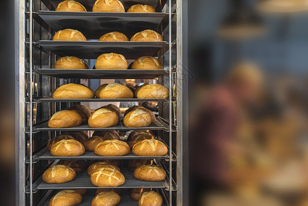 在金属架式车上新鲜烘烤的面包刚从满面的烤箱中取出并配有白面包背景图片