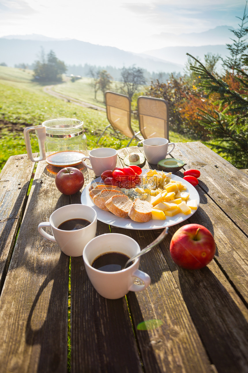 在农场野餐早上在山奶酪面包番茄鳄梨木桌上的咖啡图片