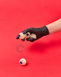 身戴黑手套的妇女将人眼睛放在红色背景上复制空间图片