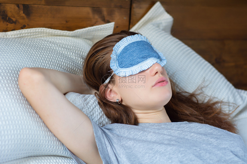 年轻女孩睡在床上时戴着眼罩图片