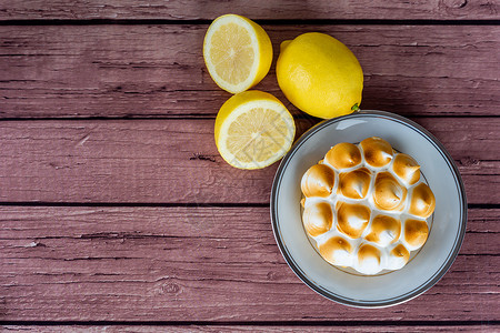 新鲜自制柠檬派配有蛋白糖和木制桌上的柠檬柑橘水果高清图片