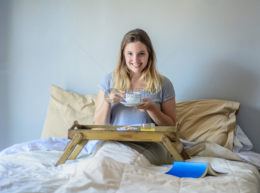女孩在床上吃早餐和喝咖啡图片