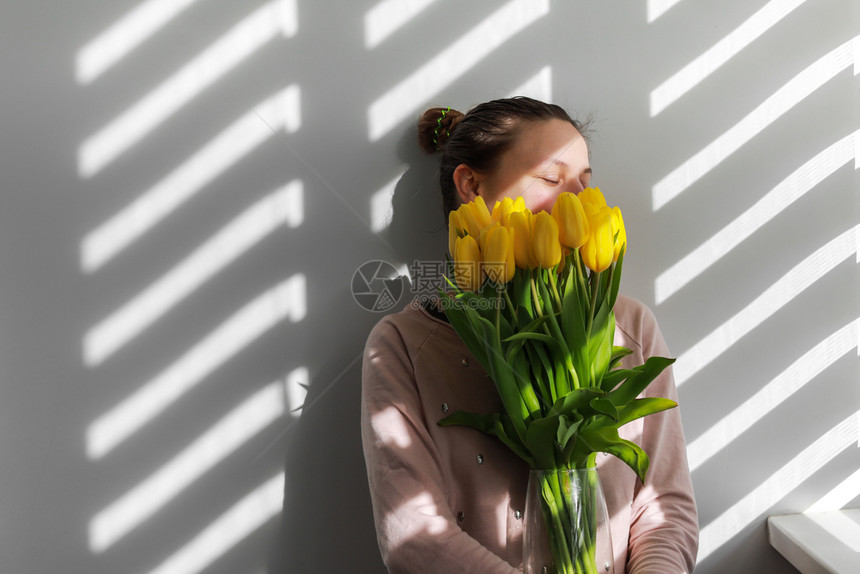 黄花郁金香的年轻女近白背景的天然肖像生活方式有郁金香的妇女近白背景的黄花郁金香天然肖像生活方式图片