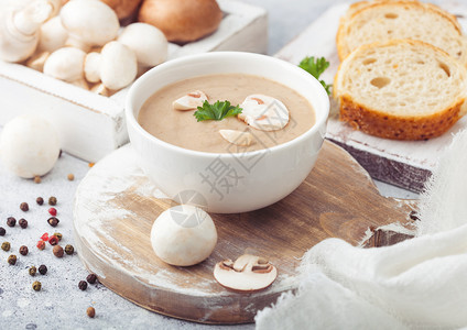 白碗盘奶油栗椰子香菇汤浅厨房背景和一盒生蘑菇新鲜面包背景图片
